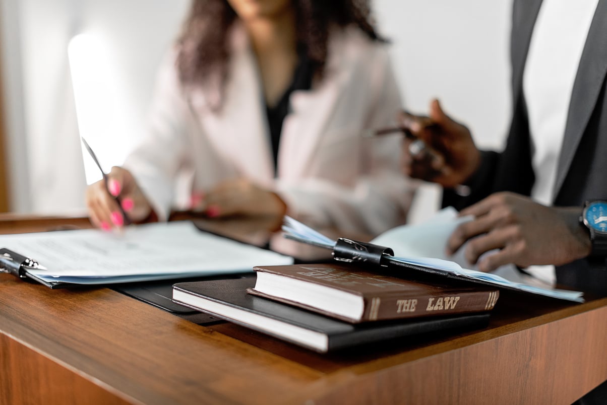 two people sitting at a desk with papers and pens