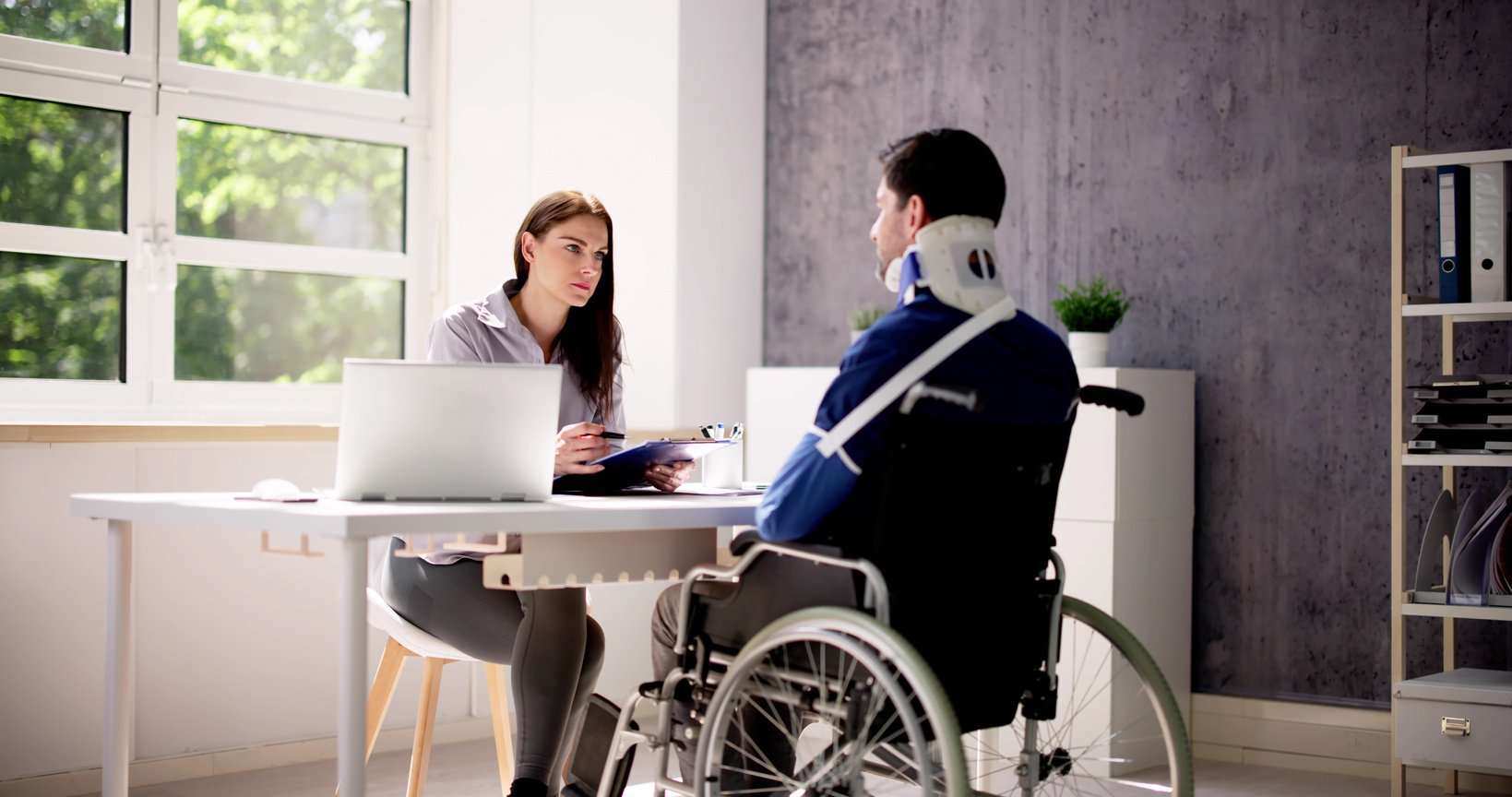 A person sitting at a desk in front of a laptop and injured client